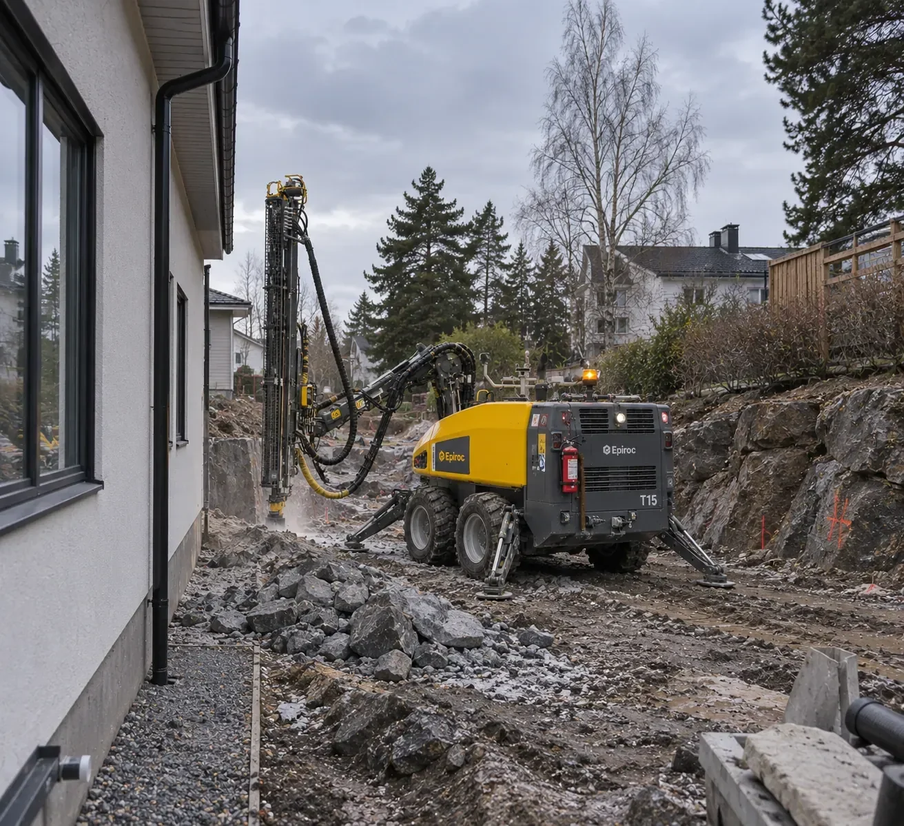 Borrigg som borrar i berg bredvid ett bostadshus